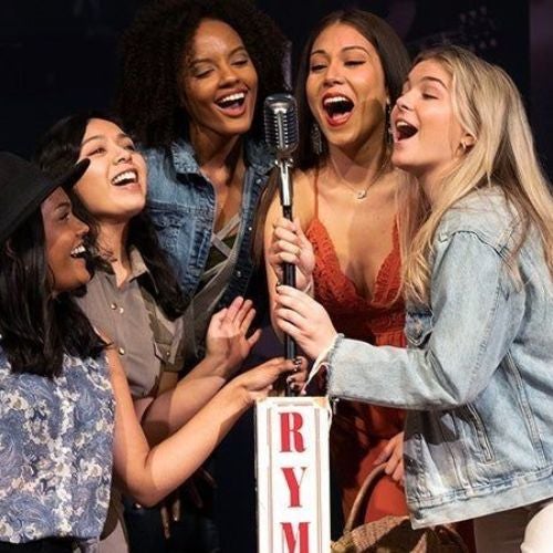 Photo of women posing with a mic stand on the stage of the Ryman